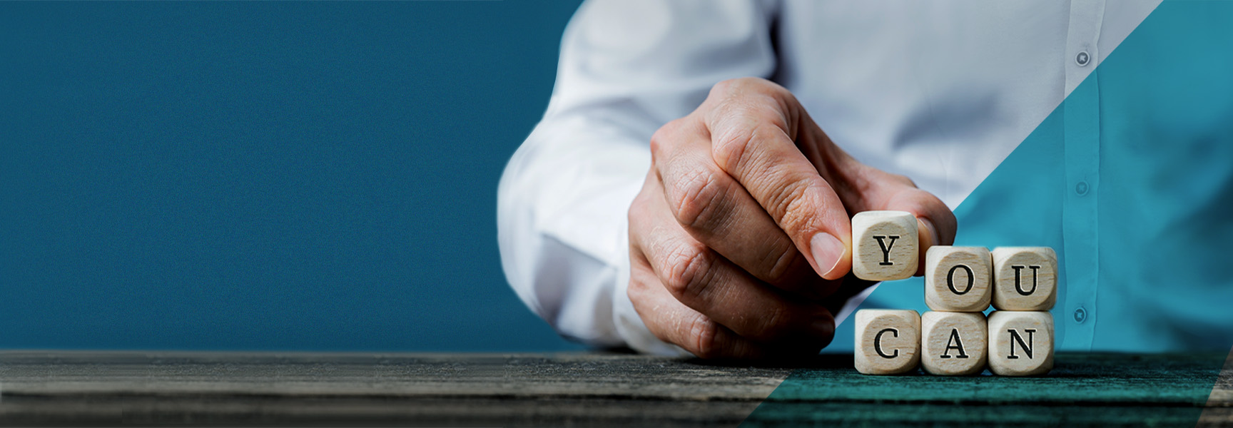 A person in a white shirt is placing wooden blocks on a table to spell YOU CAN. The background is a gradient of dark blue to teal. The image conveys a message of encouragement and possibility.