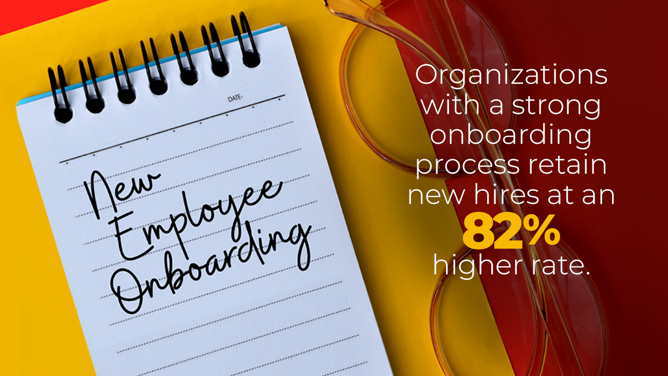 A notepad with New Employee Onboarding written on it is placed on a yellow and red background. Nearby are a pair of glasses. Text reads, Organizations with a strong onboarding process retain new hires at an 82% higher rate.